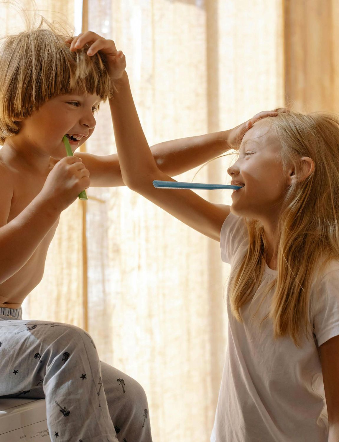 Two children laughing while brushing their teeth with DAYLY kids toothpaste