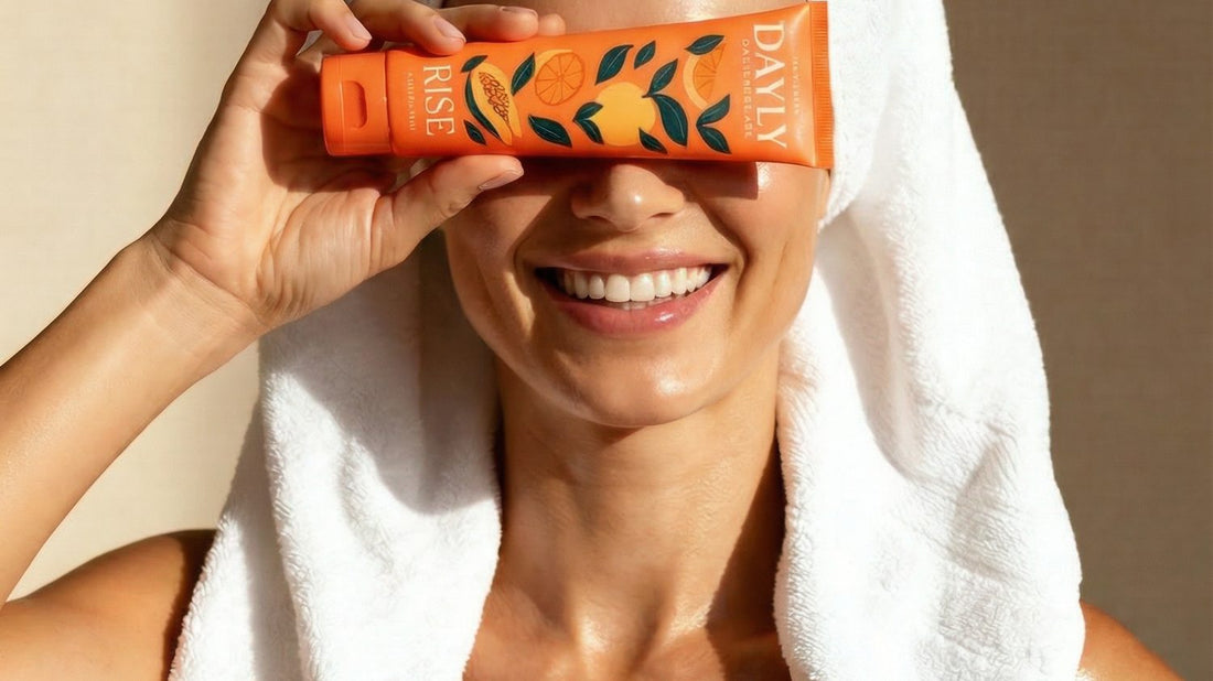 Woman in a towel smiling and holding DAYLY Rise toothpaste