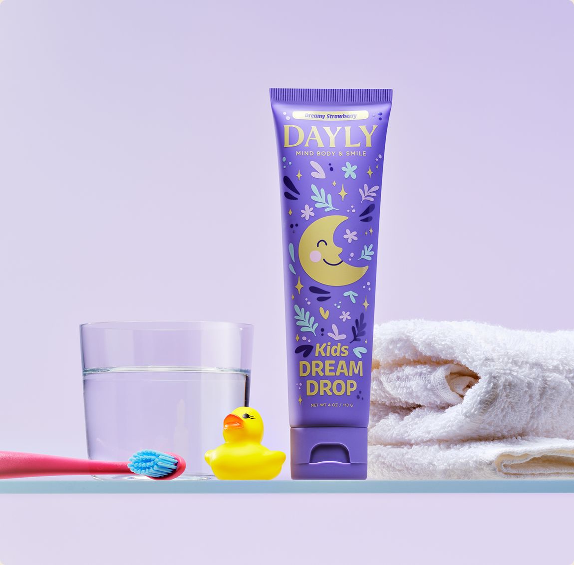 DAYLY DREAM DROP kids toothpaste on a bathroom shelf with a rubber duck and towels
