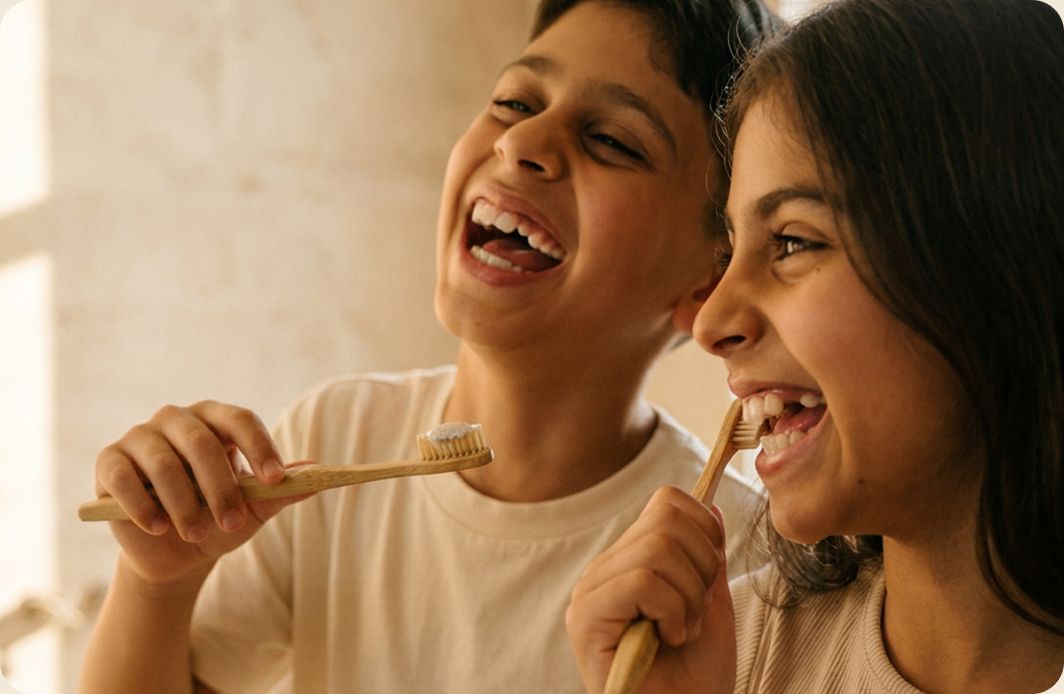 Dominic and Valentina laughing while brushing their teeth with bamboo toothbrushes